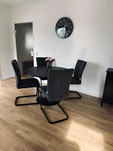 a dining room with a table and chairs and a clock at FeWo Burgblick Sonnenterrasse & Burgblick in Bad Bentheim