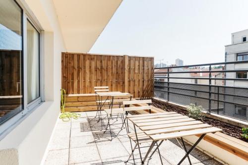 Un balcón con mesas y sillas en un edificio en GuestReady - Modern Apt in Issy-les-Moulineaux, en Issy-les-Moulineaux