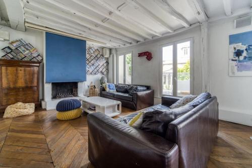 un salon avec un canapé en cuir et une cheminée dans l'établissement GuestReady - Cosy with Terrace near Passage Brady, à Paris