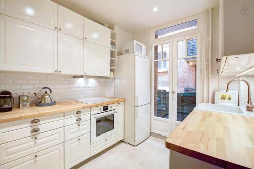 une cuisine avec des armoires blanches et un évier dans l'établissement GuestReady - Bright Flat at Porte d'Auteuil Metro, à Paris