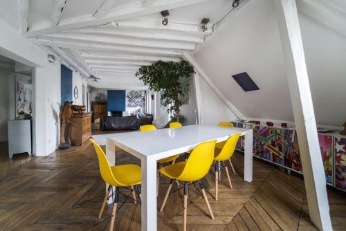 une salle à manger avec une table blanche et des chaises jaunes dans l'établissement GuestReady - Cosy with Terrace near Passage Brady, à Paris
