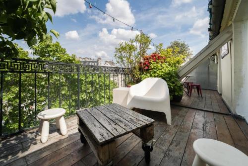 d'un balcon avec des chaises blanches et une table en bois. dans l'établissement GuestReady - Cosy with Terrace near Passage Brady, à Paris
