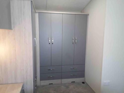 a closet with white cabinets in a room at Forestbrook - Cheerful two bedroom tiny house in Carlisle