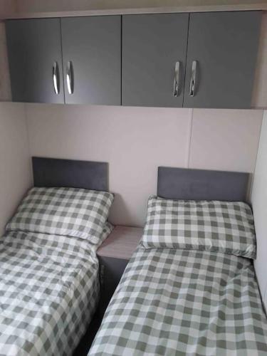 two beds sitting next to each other in a room at Forestbrook - Cheerful two bedroom tiny house in Carlisle