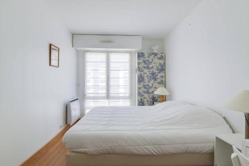 une chambre blanche avec un grand lit et une fenêtre dans l'établissement GuestReady - Chic and Luminous Apartment in Bastille, à Paris