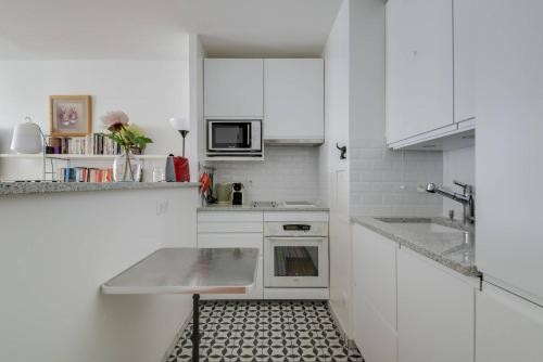 - une cuisine avec des placards blancs et du carrelage noir et blanc dans l'établissement GuestReady - Chic and Luminous Apartment in Bastille, à Paris