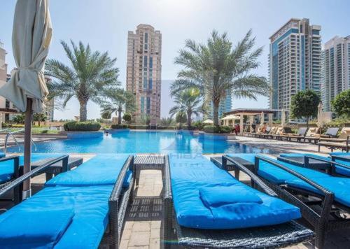 uma grande piscina com cadeiras azuis e palmeiras em GuestReady - Sunny Delights em Dubai