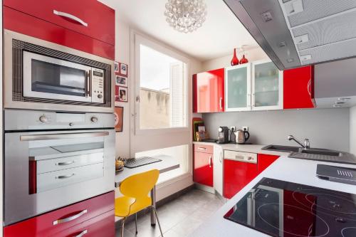 une cuisine avec des placards rouges et une chaise jaune dans l'établissement GuestReady - Spacious apartment in the heart of the Marais, à Paris