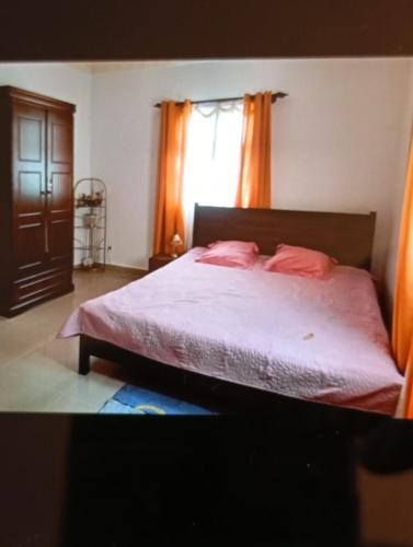 a bedroom with a bed with pink sheets and a window at Villa calme in Antananarivo