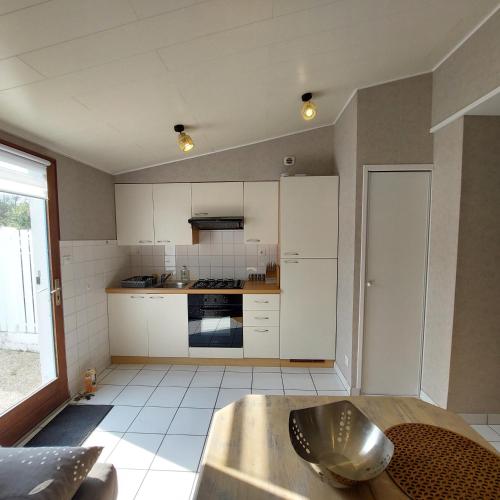 une cuisine avec des armoires blanches et un four à plaques de cuisson dans l'établissement Maison Studio La Chaume de 20 m2, à Les Sables-dʼOlonne