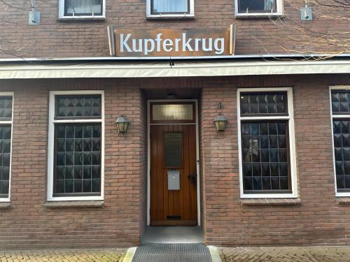 a brick building with a door and a sign on it at FeWo Kupferkrug - im Stadtzentrum in Nordhorn
