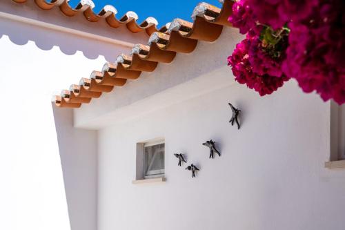 three bees hanging on the side of a white building with flowers at Casa O Cantinho Algarvio in Odeceixe