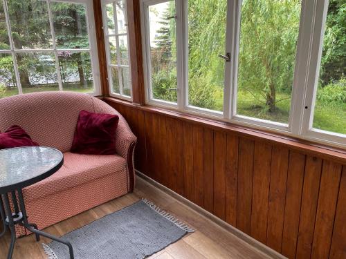 a room with a chair and a table and windows at Villa Brzozowy Gaj in Karpacz