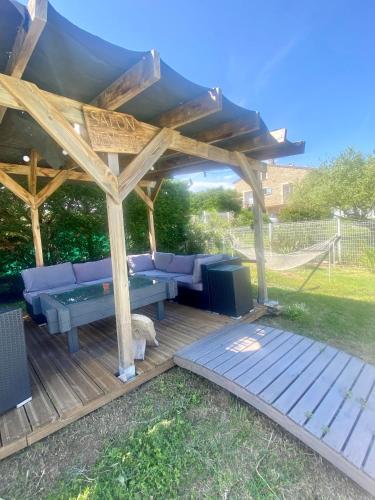 une pergola en bois avec un canapé bleu sur une terrasse dans l'établissement Gite 4p, 2 chambres, jardin, piscine à partager, à Alba-la-Romaine