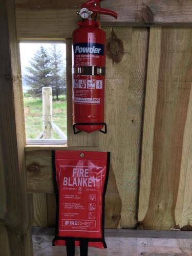 a fire extinguisher hanging on a wall next to a sign at Thainstone tipi off grid camping, on top NC500 in Lochcarron