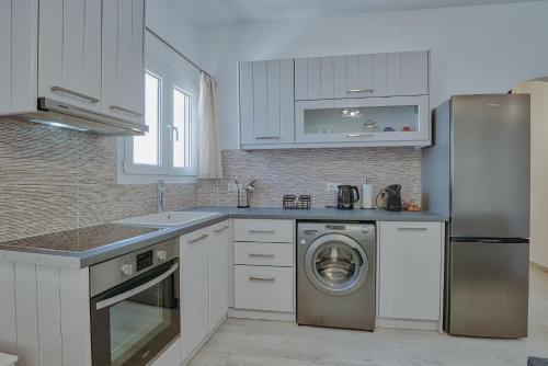 a kitchen with white cabinets and a washer at Rose House and Apartments in Andiparos