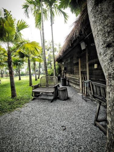 two benches sitting outside of a cabin with palm trees at Paragon Inn in Lat Krabang