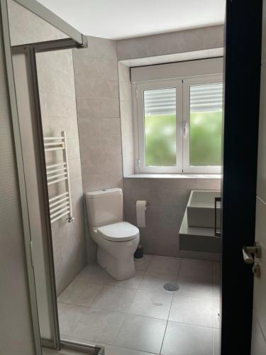 a bathroom with a toilet and a sink and a window at Granada centro, amplio, wifi y A/C in Granada