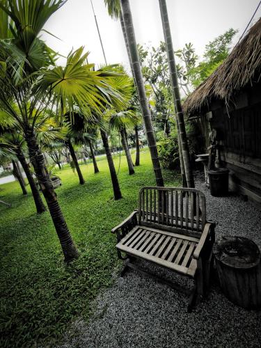 a park bench sitting next to a group of palm trees at Paragon Inn in Lat Krabang