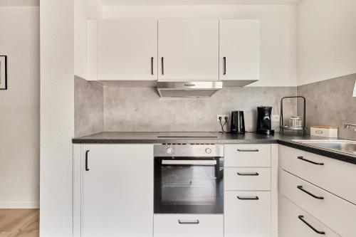 eine weiße Küche mit Herd und Spüle in der Unterkunft Elegantes 2 Zimmer Apartment Neubau Top Lage in Mannheim