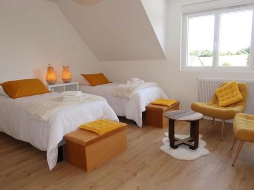 une chambre blanche avec deux lits et une chaise dans l'établissement Villa Ty PY : Charme moderne et tranquillité, à Fouesnant
