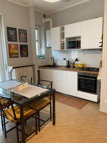 una cocina con armarios blancos y una mesa con sillas. en A Casa di Katia, en Collegno