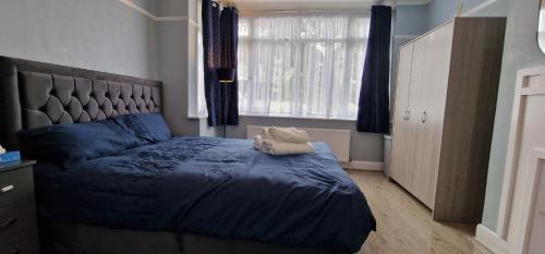 Streatham ValeにあるRowan Crescent's Luxury Stay-In4のベッドルーム1室(青い掛け布団、窓付)