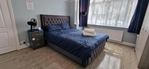 a bedroom with a bed with a blue comforter at Rowan Crescent's Luxury Stay-In4 in Streatham Vale
