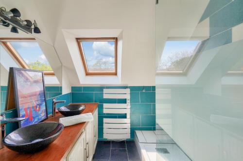 La salle de bains est pourvue de 2 lavabos et de carrelage bleu. dans l'établissement Maison coup de coeur pour 6, pays Bigouden, à Combrit