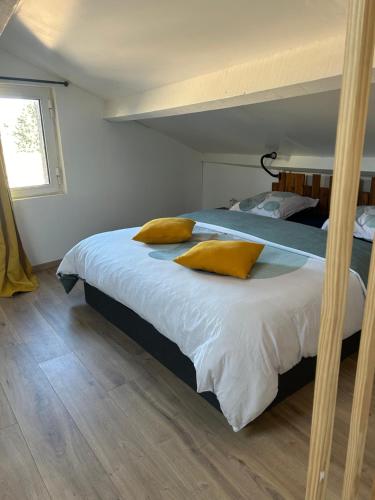 Chez Romain et Saphie في ليه بو دو بروفنس: غرفة نوم عليها سرير ومخدات صفراء