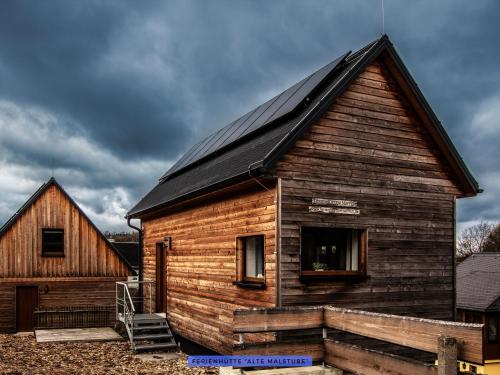 a wooden house with a black roof and a barn at Ferienhäuser Seiffen in Seiffen