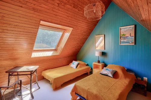 une chambre mansardée avec deux lits et une fenêtre dans l'établissement Jolie maison familiale et colorée pour 6, au Guilvinec