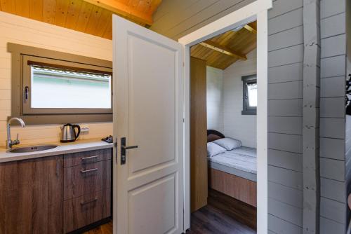 a door leading into a tiny house kitchen with a bed at Nameliai Penkios gulbės in Šventoji