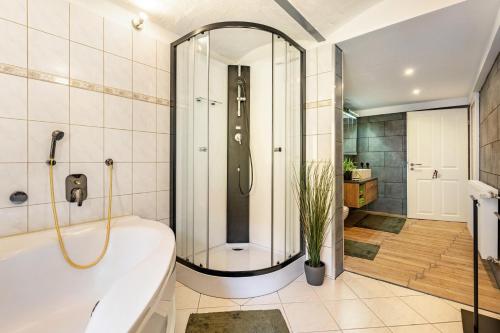 a bathroom with a tub and a shower with a plant at Ferienwohnung Am Mühlbach in Klipphausen