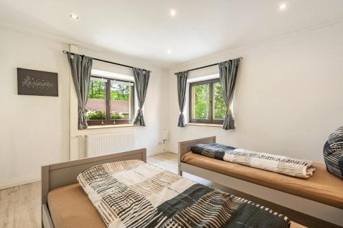 two beds in a room with two windows at Ferienwohnung Am Mühlbach in Klipphausen