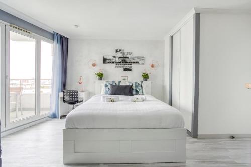 Un dormitorio blanco con una cama y una ventana grande. en Joli studio à Courbevoie - La Defense, en Courbevoie