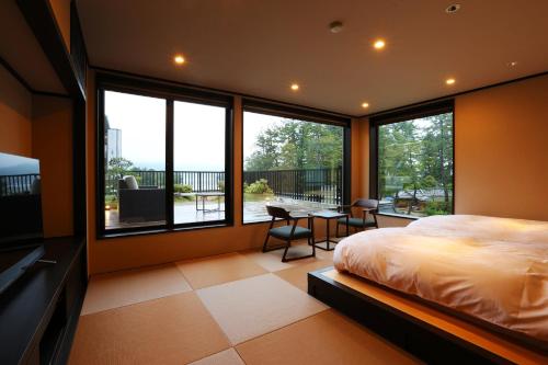 1 dormitorio con 1 cama, mesa y sillas en Taikyourou, en Miyazu