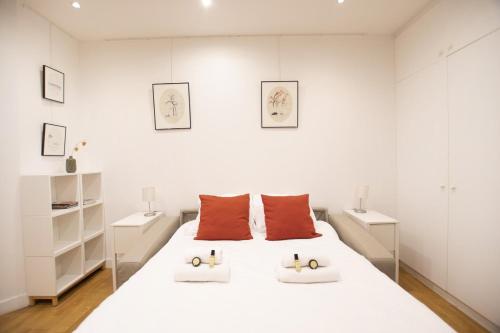 a white bedroom with a large white bed with orange pillows at GuestReady - Charming Studio – 5 mins to Pantheon in Paris