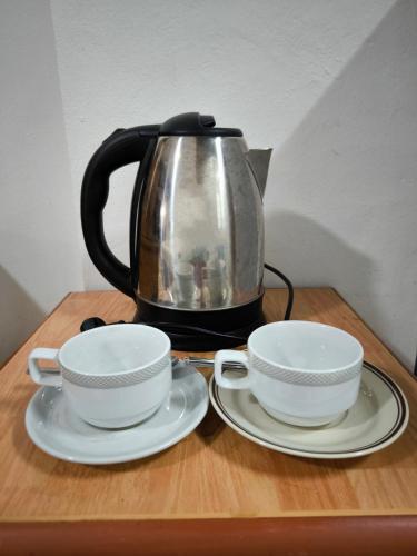 une bouilloire et deux tasses sur une table en bois dans l'établissement Arcadia Mansion, à Pattaya