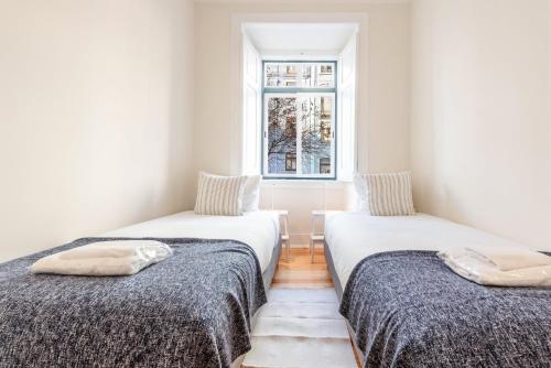 two beds in a room with a window at GuestReady - Castle - Apt for 4 guests in Saldanha in Lisbon