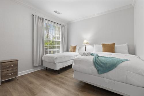 a white bedroom with two beds and a window at Near Disney w/ pool-3BR/2BA-Spacious & Cozy Condo in Davenport
