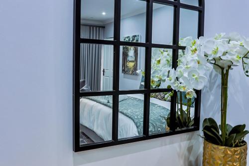a mirror in a room with a bed and flowers at Siesta Manor Guesthouse in Mokopane