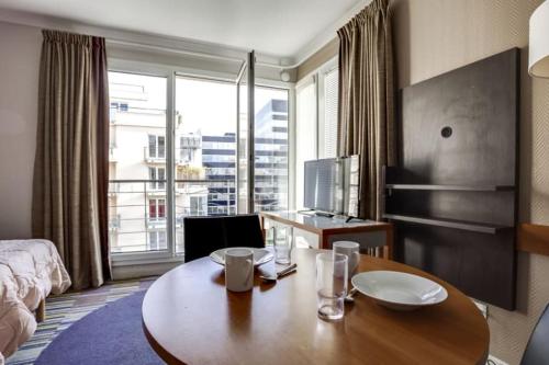 a hotel room with a table and a large window at GuestReady - Studio near Porte de Versailles Metro in Issy-les-Moulineaux