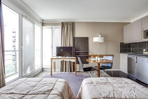a bedroom with a bed and a table and a kitchen at GuestReady - Studio near Porte de Versailles Metro in Issy-les-Moulineaux