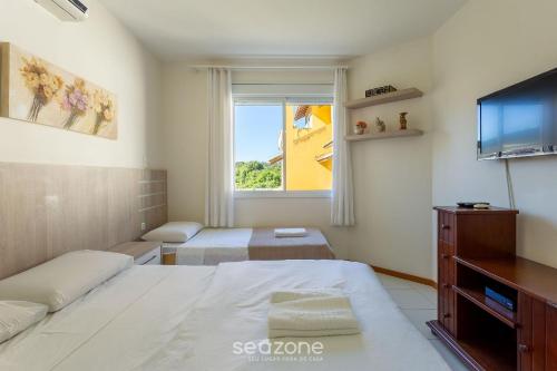 a bedroom with two beds and a flat screen tv at Casa em condo com piscina, a 300m da praia ALI024 in Florianópolis
