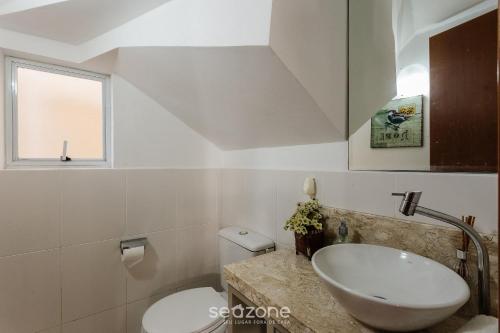 a white bathroom with a sink and a toilet at Casa em condo com piscina, a 300m da praia ALI024 in Florianópolis
