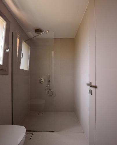 a bathroom with a shower with a glass door at Kalestesia Suites in Akrotiri
