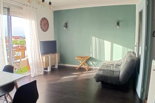 un salon avec une chaise et un réveil sur le mur dans l'établissement Appartement centre Canet plage 200m de la mer, à Canet