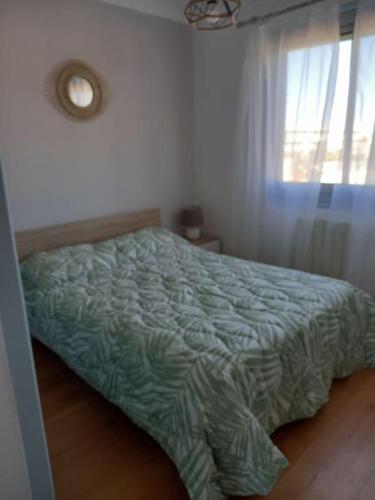 - une chambre avec un lit doté d'une couette verte et d'une fenêtre dans l'établissement Appartement centre Canet plage 200m de la mer, à Canet