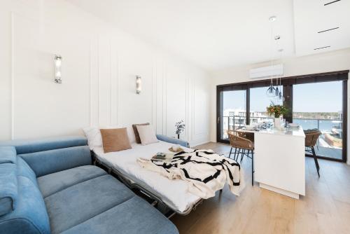 a living room with a blue couch and a table at Sol Marina Resort Wyspa Sobieszewska I - LoftAffair Collection in Wiślinka